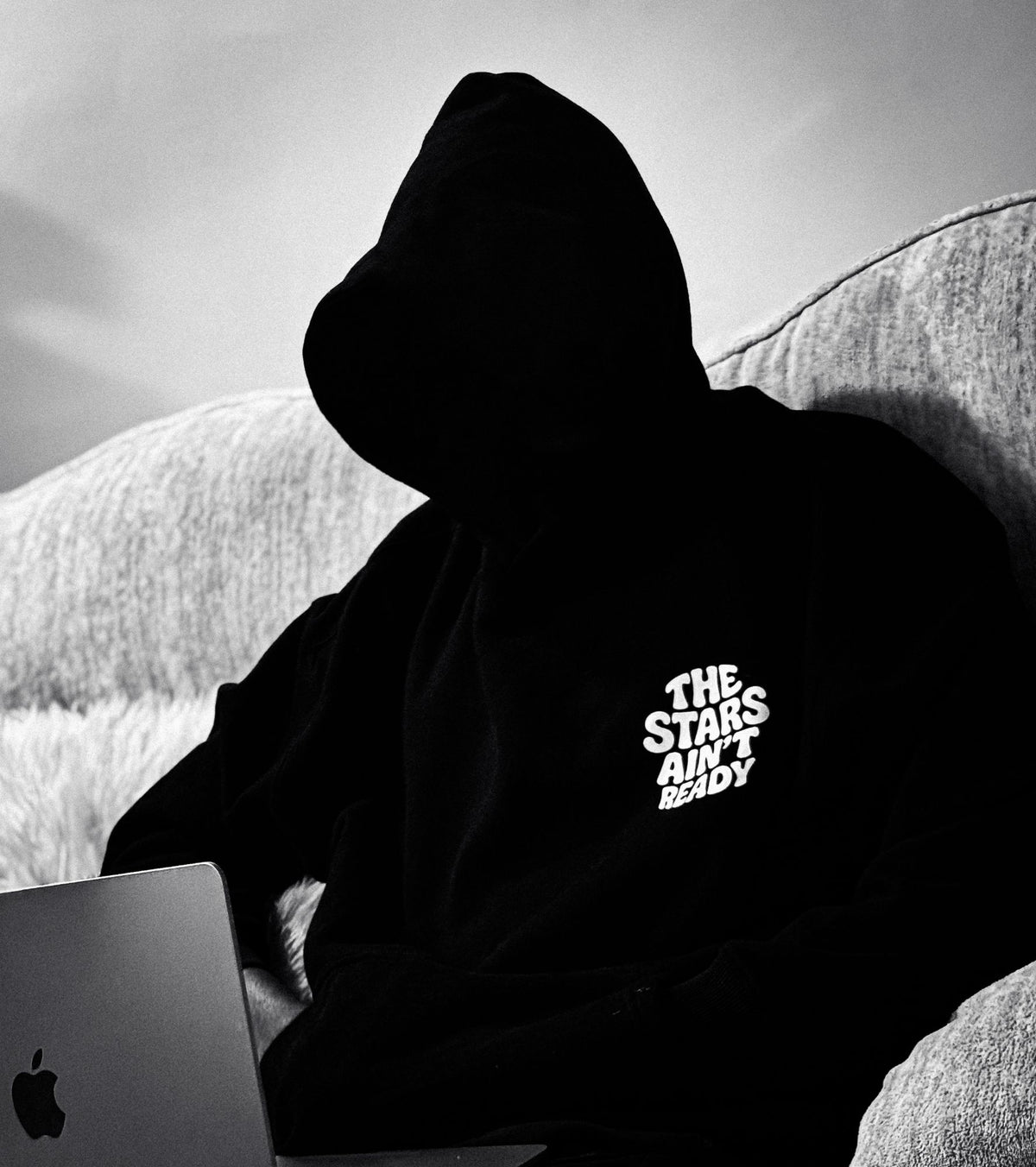 Silhouette en hoodie noir travaillant sur un ordinateur, en noir et blanc