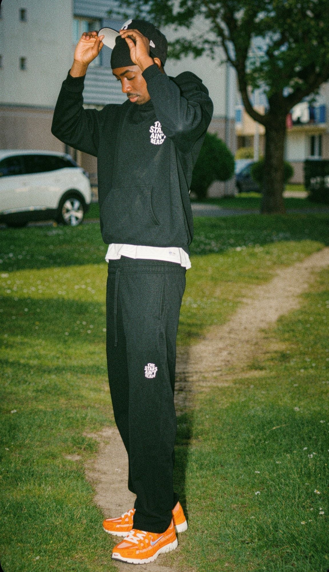 Bamba, fondateur de GRAND B., en ensemble noir dans un parc